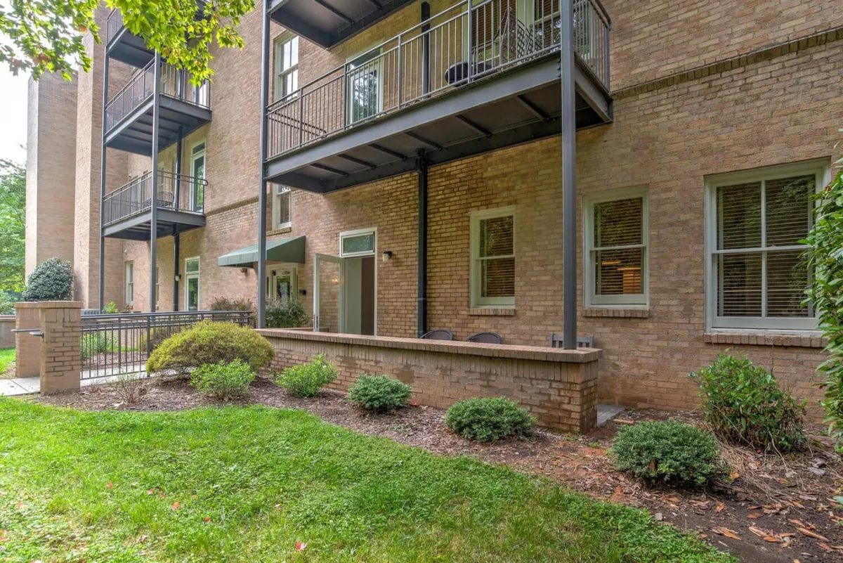 The image shows the exterior of a building with balconies overlooking lush greenery and a brick wall, offering inviting communal outdoor spaces. People could relax in the garden or enjoy views from the balcony, hinting at restful moments after a day out.